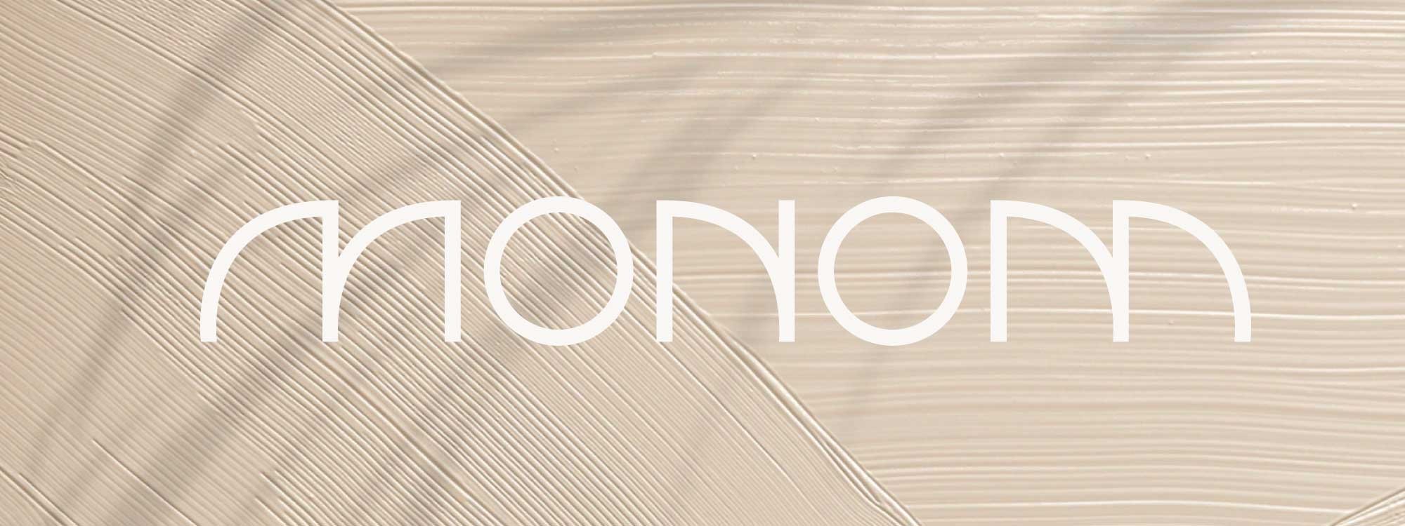 Logotype du studio Monom en blanc superposé sur une photographie de texture beige conçu par ÈS.B Studio.